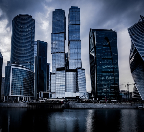 Vertical slider low angle shot grey skyscrapers front river dark cloudy sky