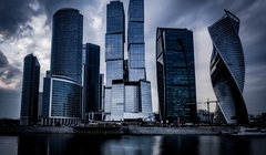 Wide thumb low angle shot grey skyscrapers front river dark cloudy sky